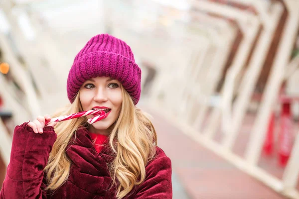 Чудова блондинка в червоному в'язаному капелюсі позує з цукерковою тростиною — стокове фото