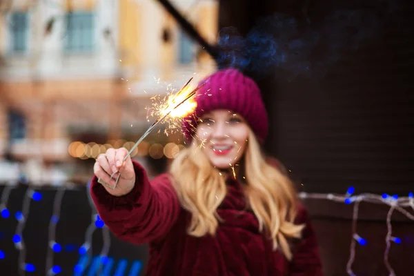 Cool  blonde woman holding glowing sparklers at the Christmas tr — Stock Photo, Image
