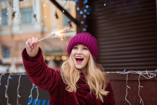 Expressive young woman dressed in warm clothes, holding glowing — Stock Photo, Image