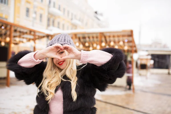 Positive blonde model making heart symbol with her hands at the — Stock Photo, Image