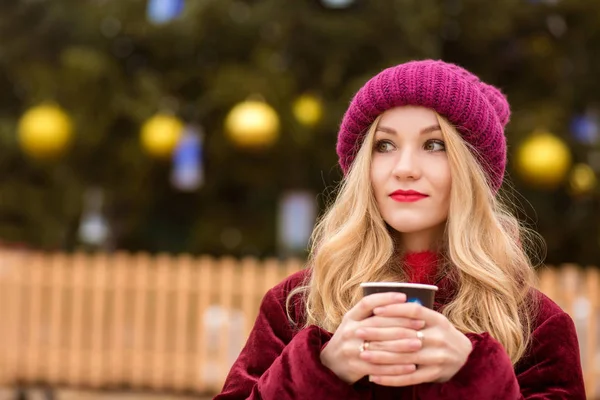 Attractive blonde woman drinking coffee near the Cristmas tree o — Stock Photo, Image