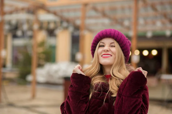 Funny young model wearing red knitted hat and winter coat, posin — Stock Photo, Image