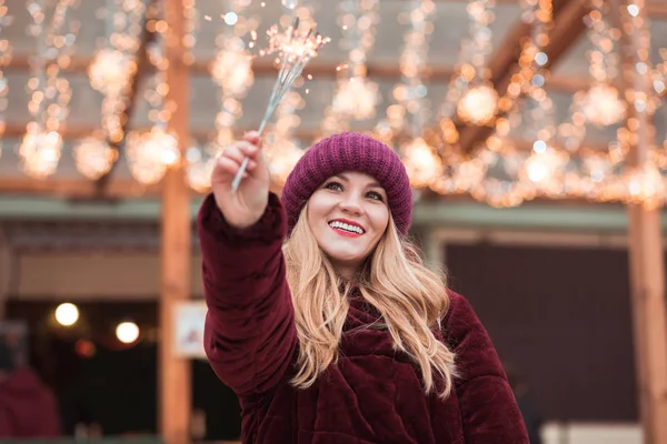 Pleased blonde girl dressed in stylish clothes, holding glowing — Stock Photo, Image