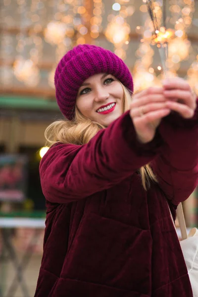 Cheerful blonde girl dressed in stylish clothes, holding glowing — Stock Photo, Image