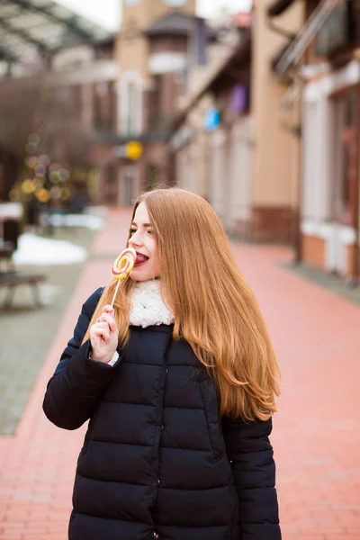 Stunning red haired woman eating colorful Christmas candy at the — Stock Photo, Image