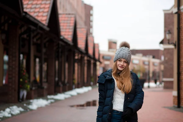 Cool blonde woman wearing black winter coat and knitted hat posi — Stock Photo, Image