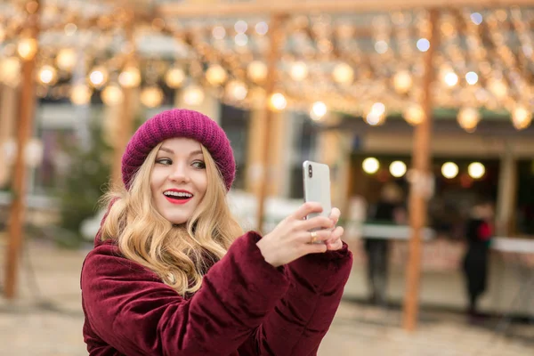 Gorgeous blonde woman dressed in warm clothes making selfie at t — Stock Photo, Image