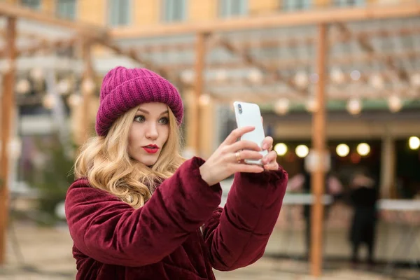 Yllättynyt blondi nainen pukeutunut trendikkäitä vaatteita joten selfie — kuvapankkivalokuva