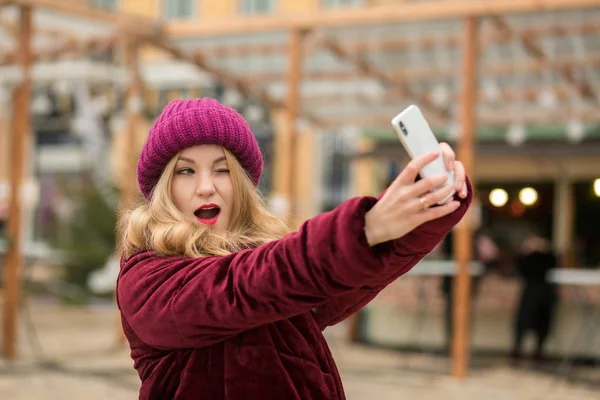 Emotional blonde woman dressed in warm clothes making selfie at — Stock Photo, Image