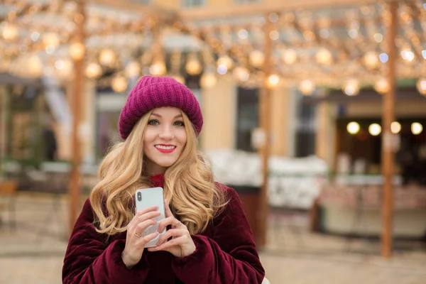 Cheerful young woman holding a mobile phone, standing at the gar — Stock Photo, Image