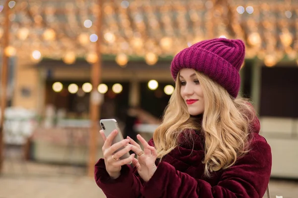 Belle femme blonde tapant un message sur un téléphone portable, stand — Photo