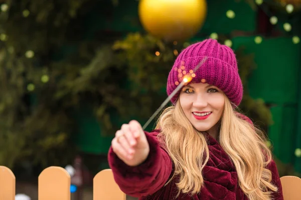 Cheerful blonde woman dressed in trendy apparel, holding sparkli — Stock Photo, Image