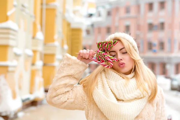 Joyful blonde woman with long hair wearing warm knitted hat, hol — Stock Photo, Image