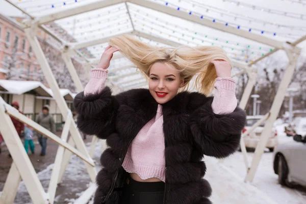 Ausdrucksstarke junge Frau im warmen Pelzmantel posiert mit Wind im Haar — Stockfoto