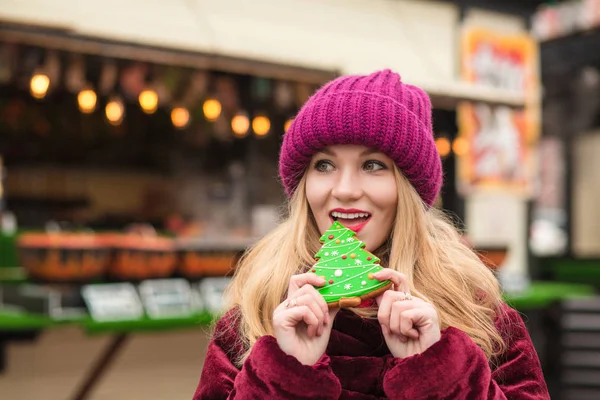 Lovely young model eating delicious christmas gingerbread at the — Stock Photo, Image