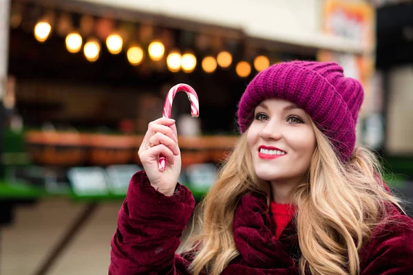 Romantic young woman posing with Christmas candy cane at the str — Stock Photo, Image