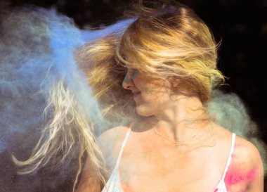 Uzun kıvırcık saçlı üzerinde çırpınan pozitif sarışın kadın Rüzgar wi