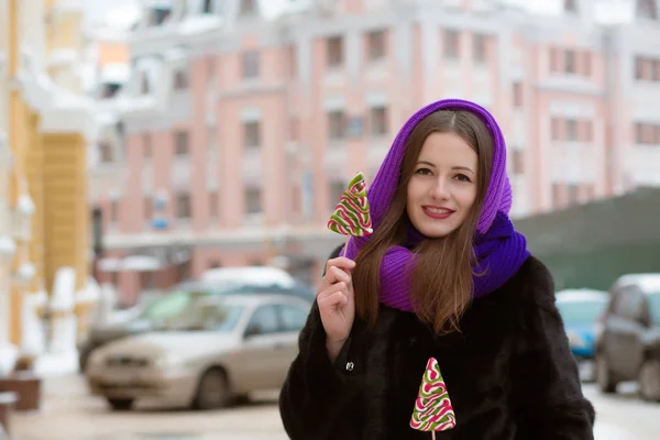 Lachende jonge vrouw in winterkleren poseren met smakelijke kleurrijke — Stockfoto