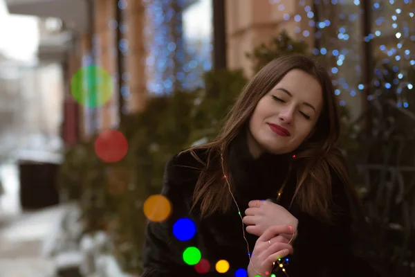 Fabulous young woman wearing fur coat posing with garland in her — Stock Photo, Image