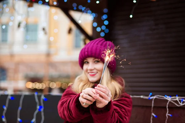 Expressive blonde girl holding glowing Bengal lights at the Chri — Stock Photo, Image