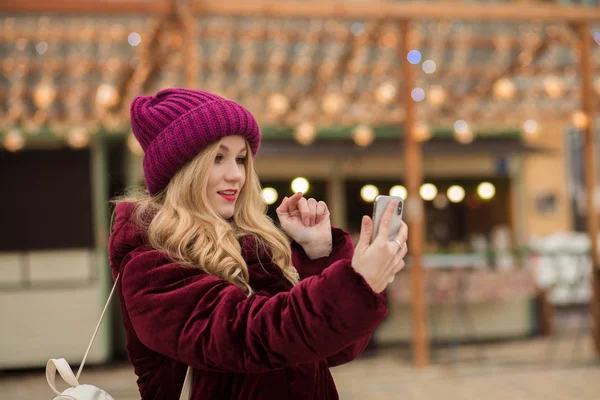 Attraktive junge Frau tippt eine Nachricht auf ein Handy, stehen — Stockfoto