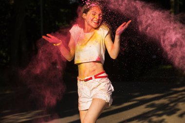 Pembe kuru bir bulut içinde poz güzel genç kadın Holi, boya