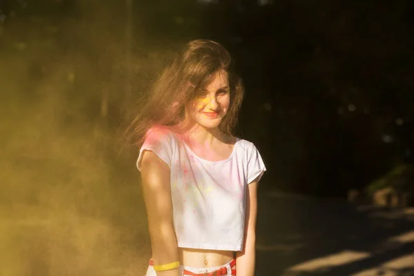 Güzel genç model sarı kuru boya bulutu içinde eğleniyor — Stok fotoğraf