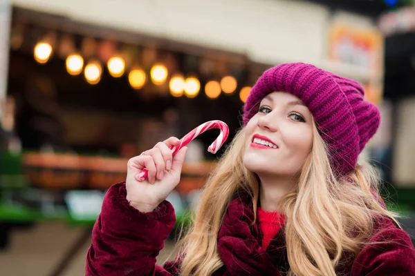 Lovely young woman posing with Christmas candy cane at the stree — Stock Photo, Image