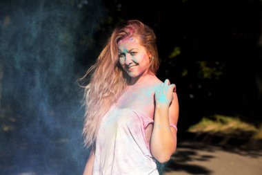 Genç ve güzel kadın kıvırcık saçlı mavi pow bulutu içinde poz