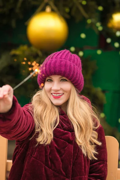 Adorable mujer rubia divirtiéndose con luces de bengala brillantes en — Foto de Stock