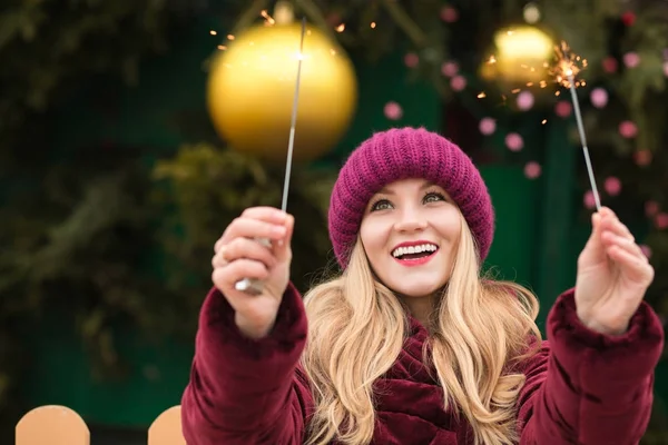 Laughing blonde woman having fun with sparkling bengal lights at — Stock Photo, Image