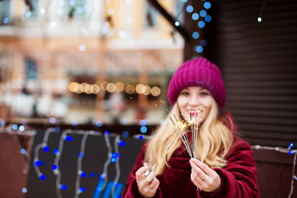 Happy blonde girl holding glowing Bengal lights at the Christmas — Stock Photo, Image