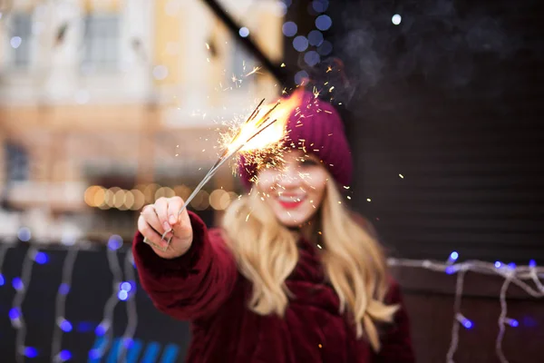 Chica rubia feliz sosteniendo luces de Bengala ardientes en la Navidad — Foto de Stock