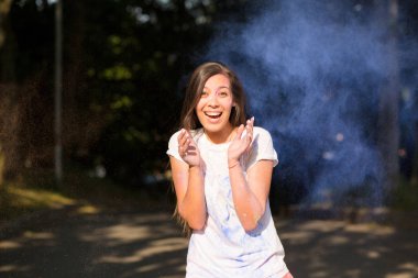 Holi boya patlayan ile eğleniyor Genç Asyalı kadın gülüyor 