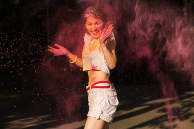 Pembe kuru boya Holi bulutu içinde poz çekici genç kadın 