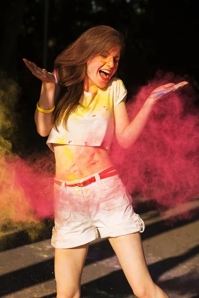 Pembe kuru boya Holi bulutu içinde poz memnun esmer kız bir