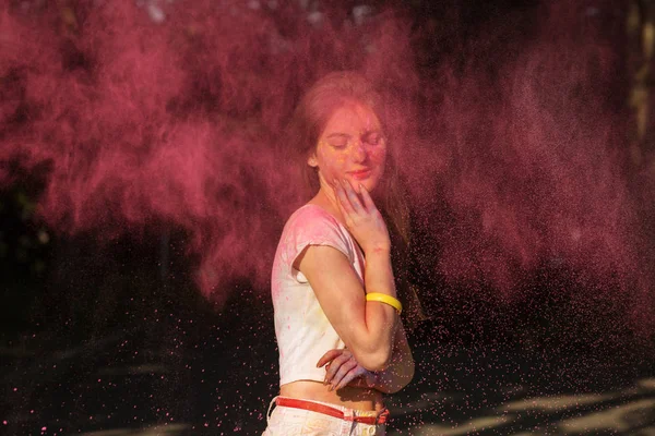 Adorable joven modelo posando con polvo rosa Holi explotando arou — Foto de Stock