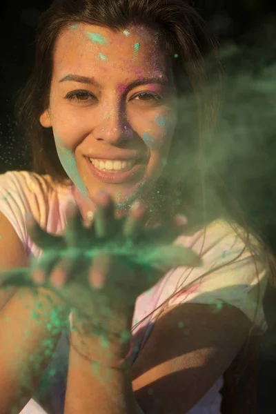 Sonriente mujer joven bronceada divirtiéndose con verde Holi pintura seca — Foto de Stock