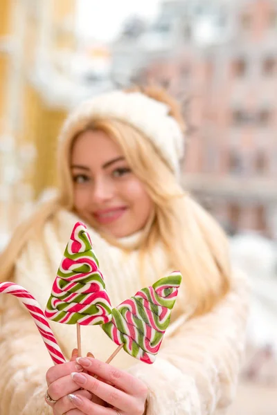 Wesoła blond dziewczyna w ciepłym kapeluszu i sierści trzyma smaczne christma — Zdjęcie stockowe