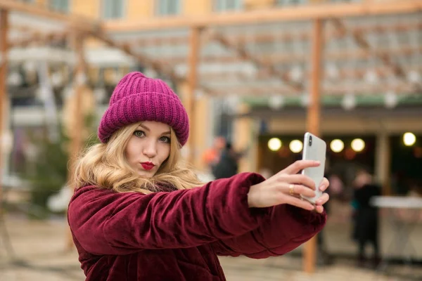 Wanita pirang bergaya mengenakan pakaian hangat membuat selfie di th — Stok Foto