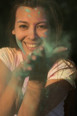 Neşeli tabaklanmış kadın yeşil Holi kuru boya ile eğleniyor 