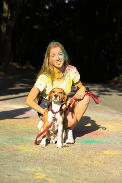 Bella donna sorridente in posa con piccolo cane domestico a Holi fes — Foto Stock