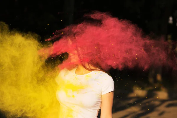 Young slim woman with exploding yellow and pink  powder celebrat — Stock Photo, Image