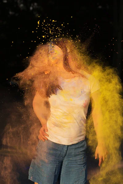 Positive brunette model covered with yellow powder celebrating H