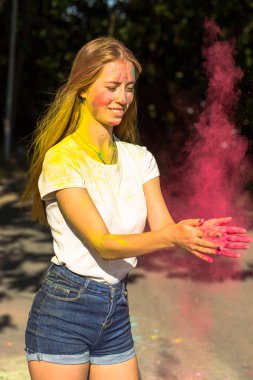 Pembe kuru boya Holi parkta oynarken mutlu sarışın kadın