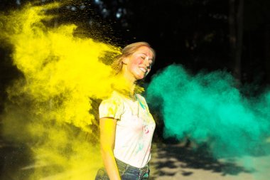Sarı ve yeşil kuru boya ile Holi oynayan neşeli genç kadın