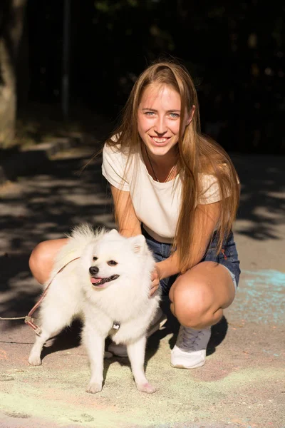 Giovane donna sorridente in posa con piccolo cane soffice a Holi festiv — Foto Stock