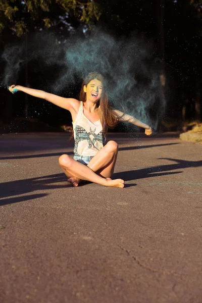 Holi boya, aspha üzerinde oturan savurma mutlu esmer modeli — Stok fotoğraf