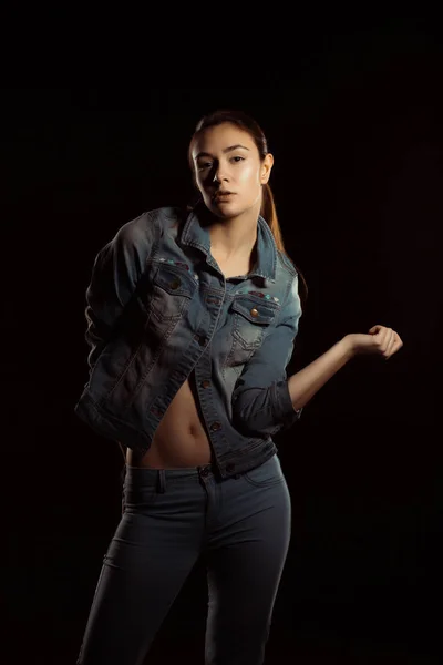 Lovely young woman in trendy jeans outfit posing in the shadows — Stock Photo, Image