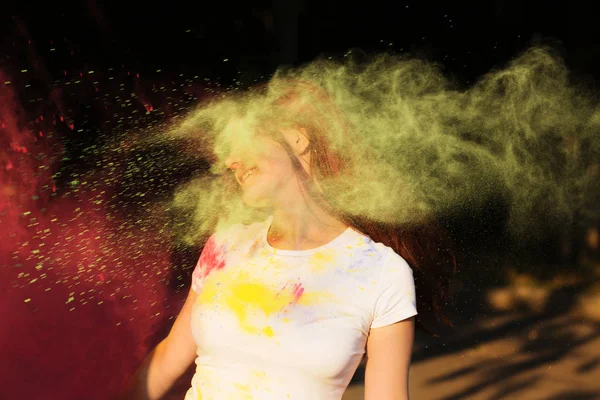 Mujer morena positiva con explosión de polvo amarillo y rosa ce — Foto de Stock